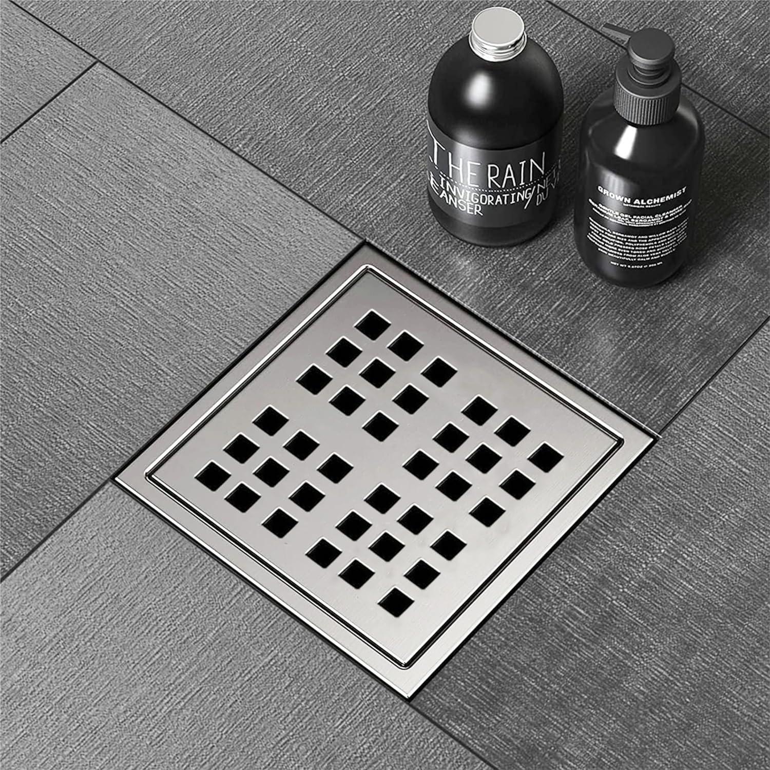 Stainless steel square floor drain with modern grid design on grey bathroom tiles
