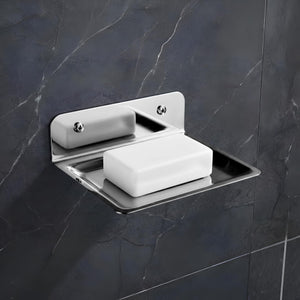 Wall-mounted soap dish with a bar of soap on a dark tiled wall