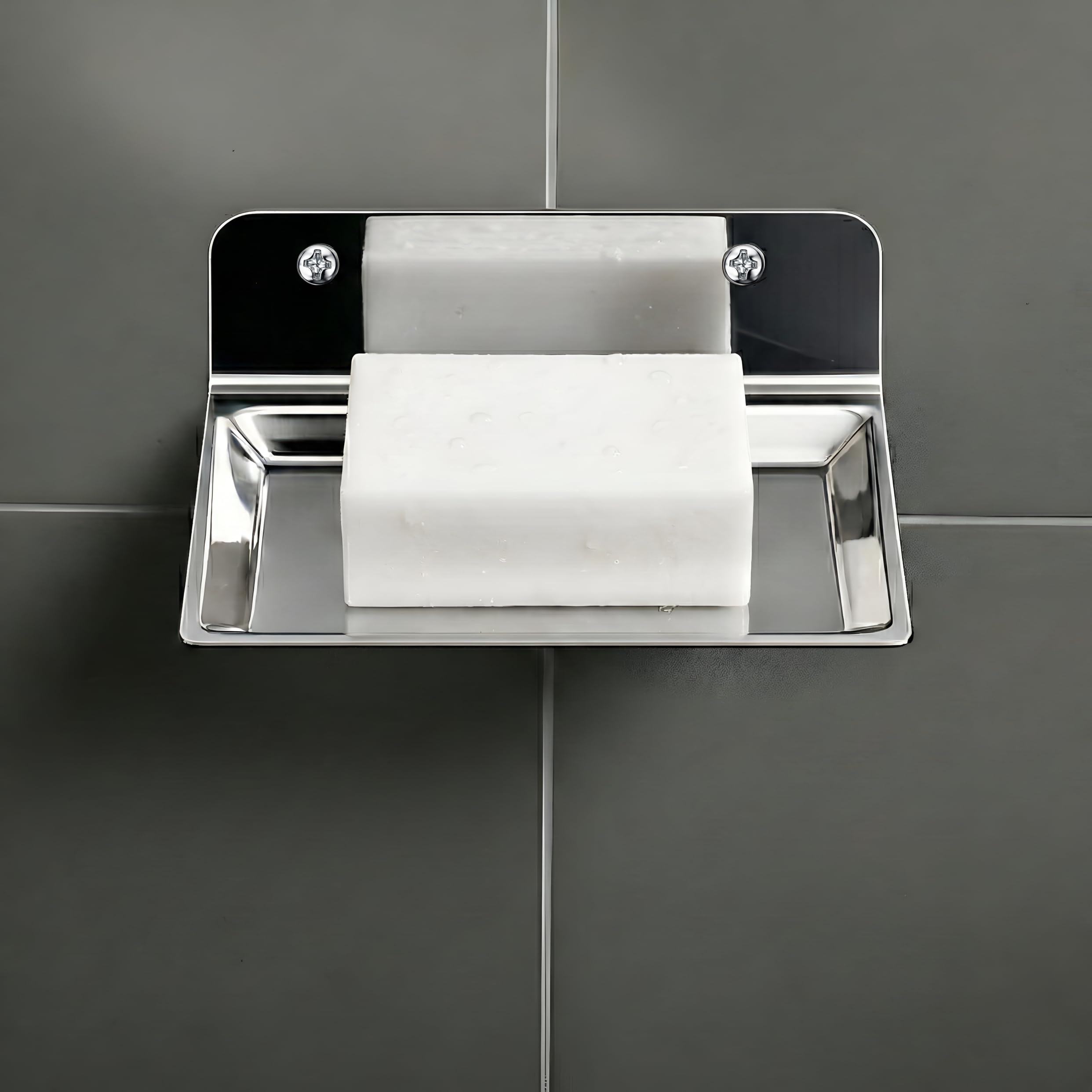 Metallic soap dish with a bar of soap on a gray tiled wall