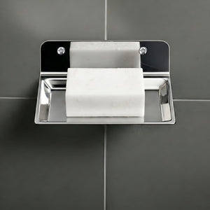 Metallic soap dish with a bar of soap on a gray tiled wall